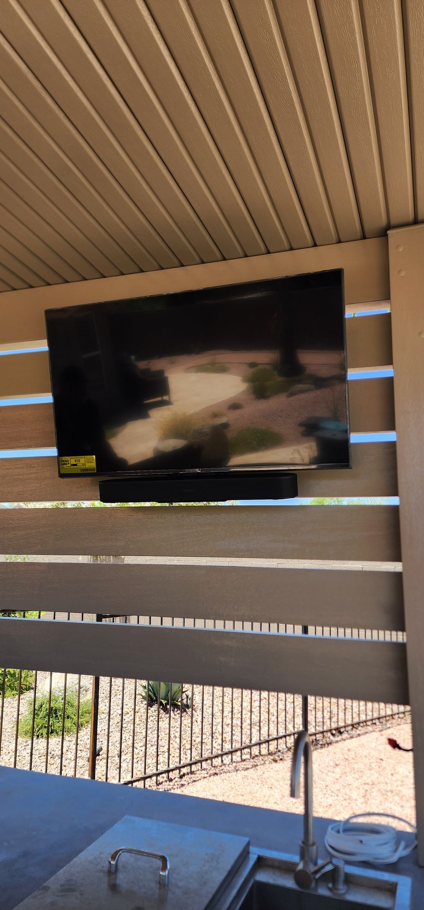 A flat screen tv is hanging from the ceiling above a sink.