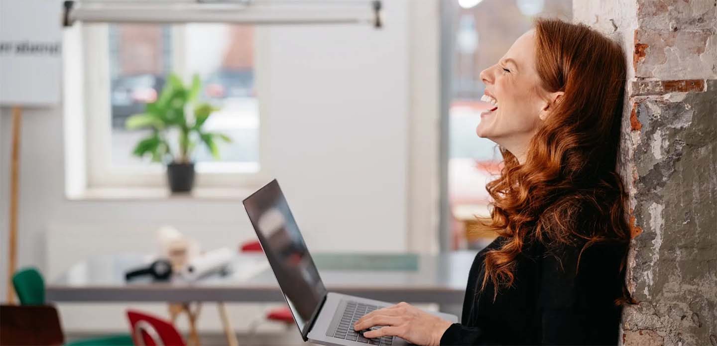 Woman Sitting At Laptop Laughing