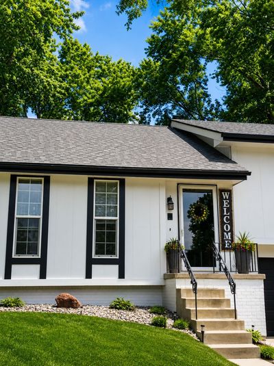 White house exterior with black trim, front steps, and a WELCOME sign by the door