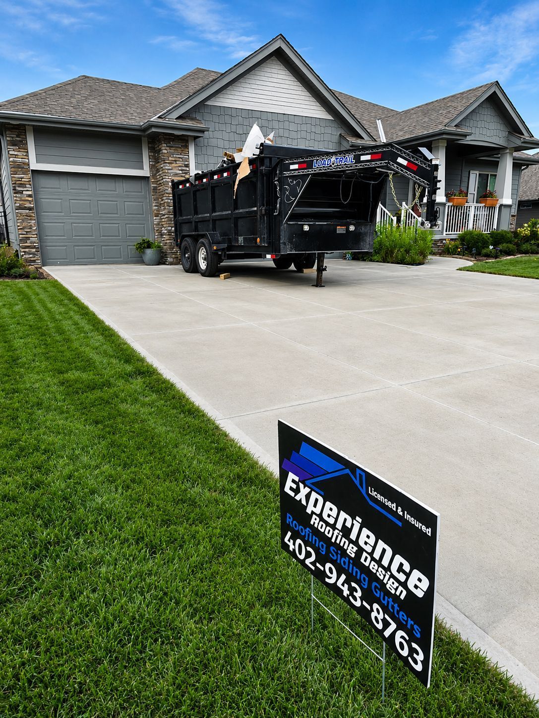 Black landscaping dumpster in a suburban driveway outside a gray house, with an Experience sign in the foreground