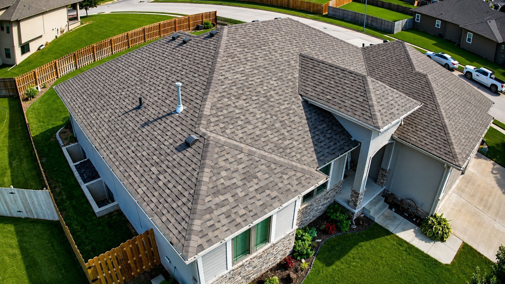 Aerial view of a suburban house with a gray shingled roof and attached driveway.