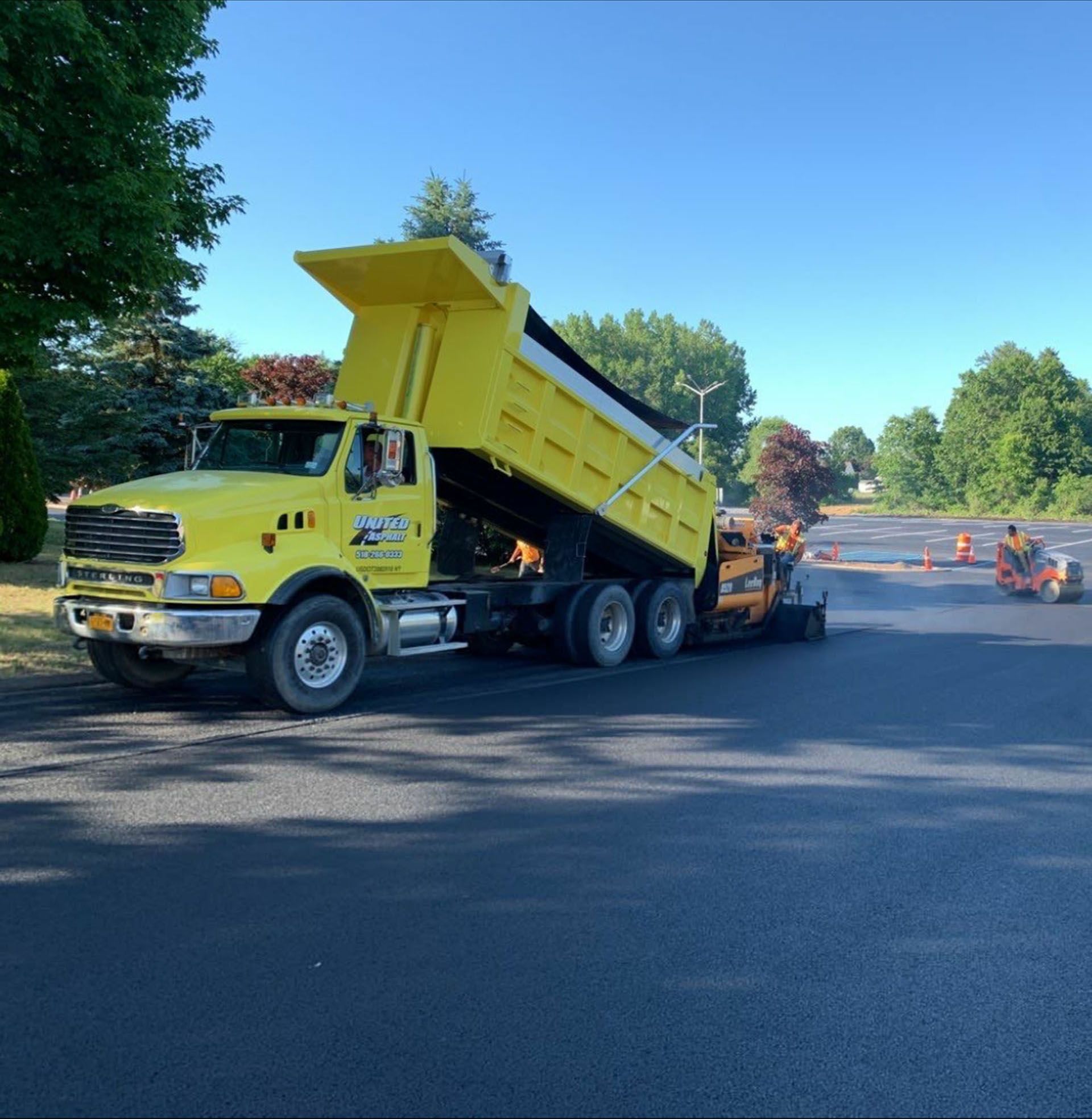 a yellow dump truck is pouring asphalt