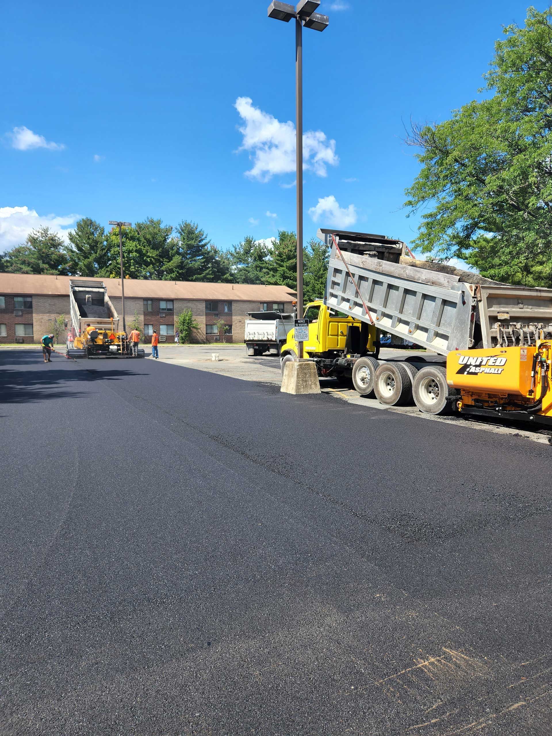 a dump truck is being loaded with asphalt in a parking lot .