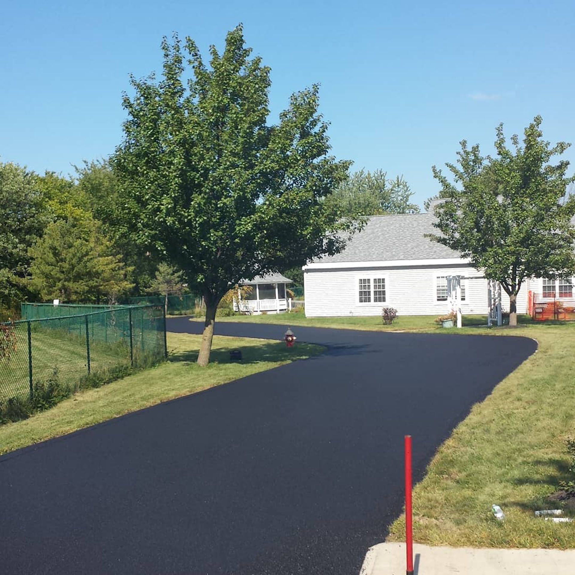 a smooth new driveway with a white house in the background