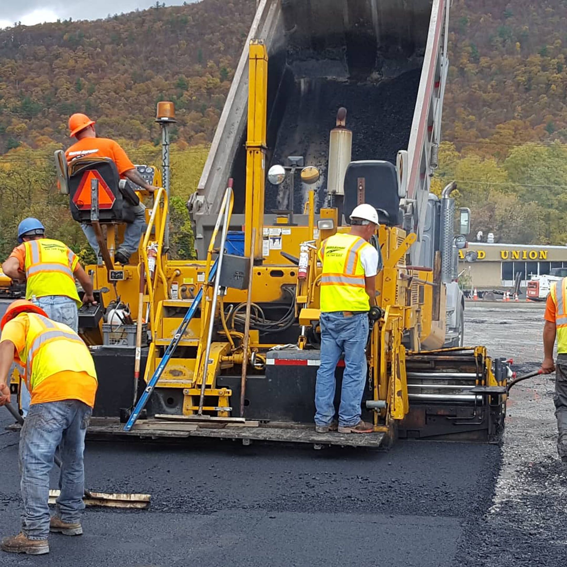 a group of paving workers are working on a road