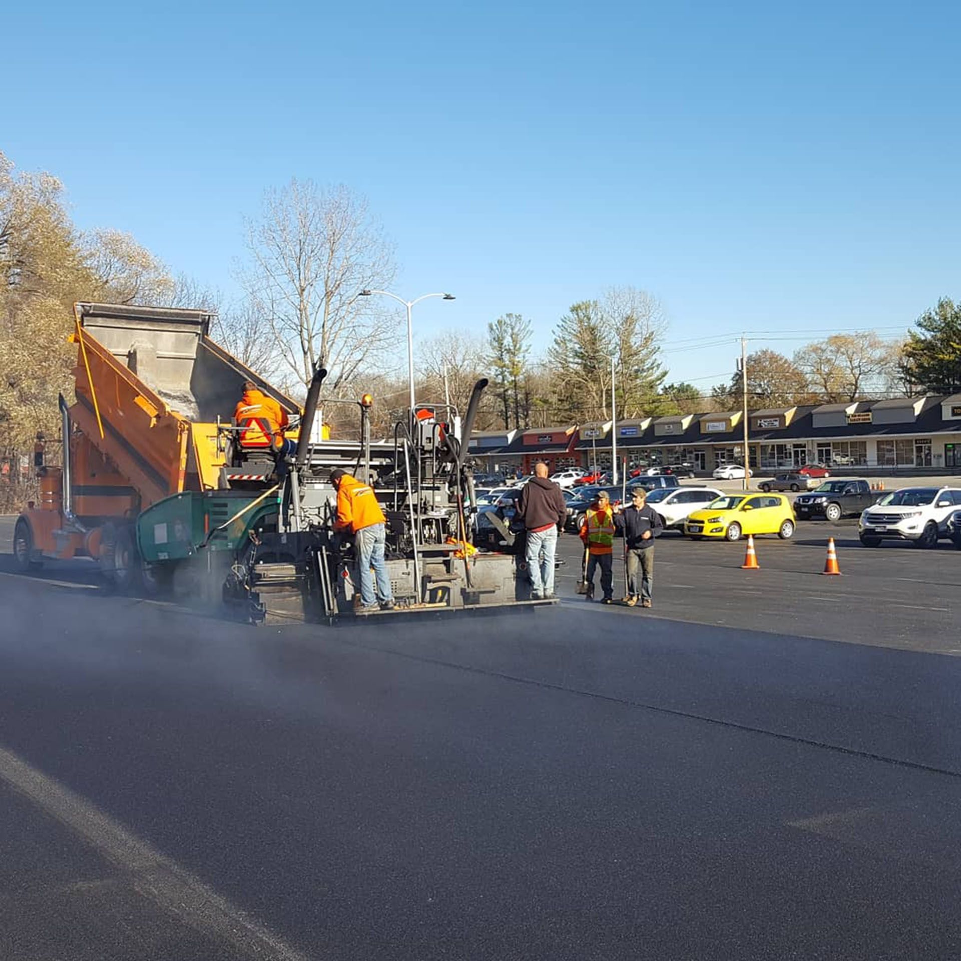 a group of construction workers are working on a road in a parking lot .