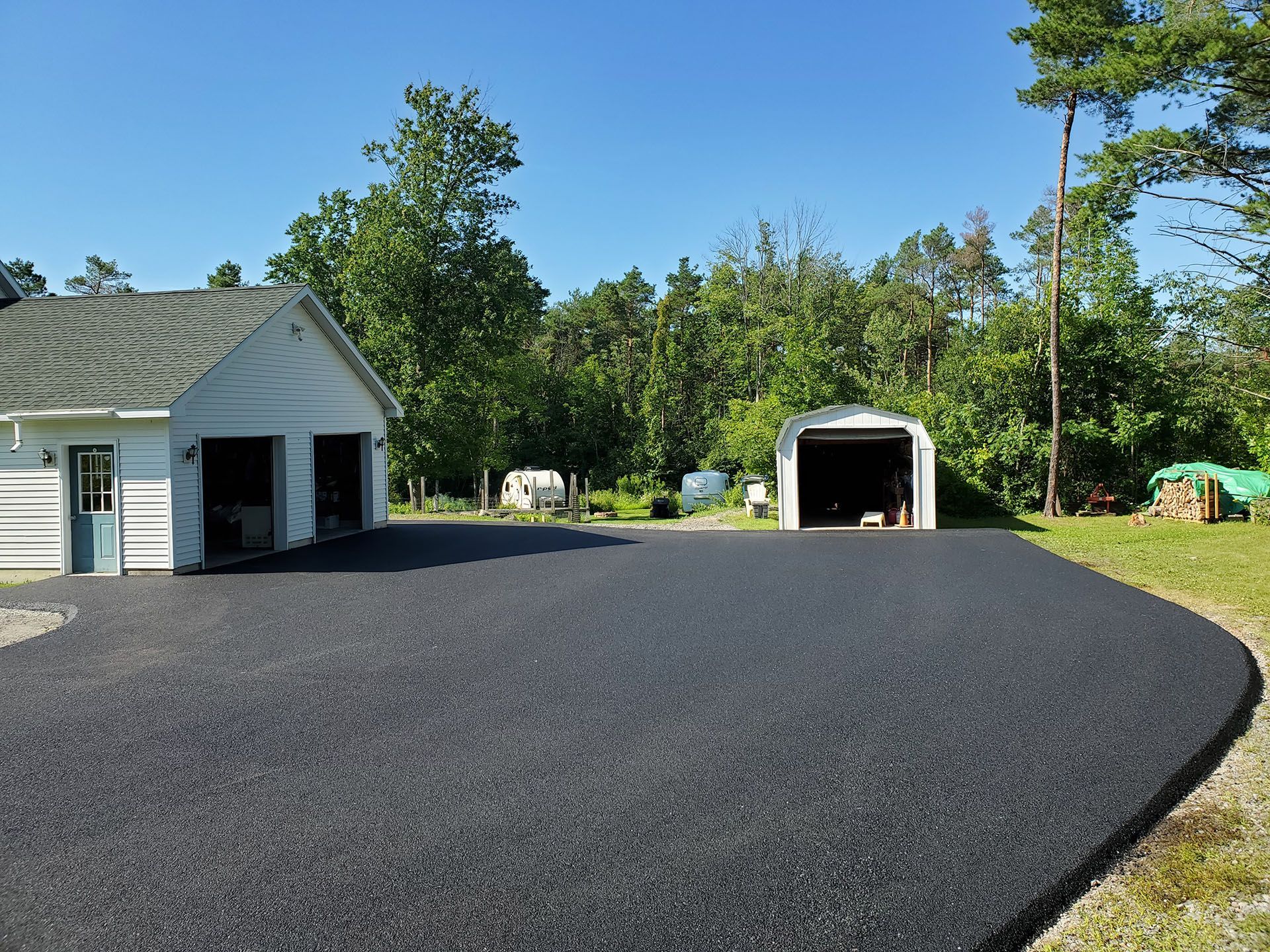 a new driveway with a garage and a shed in the background