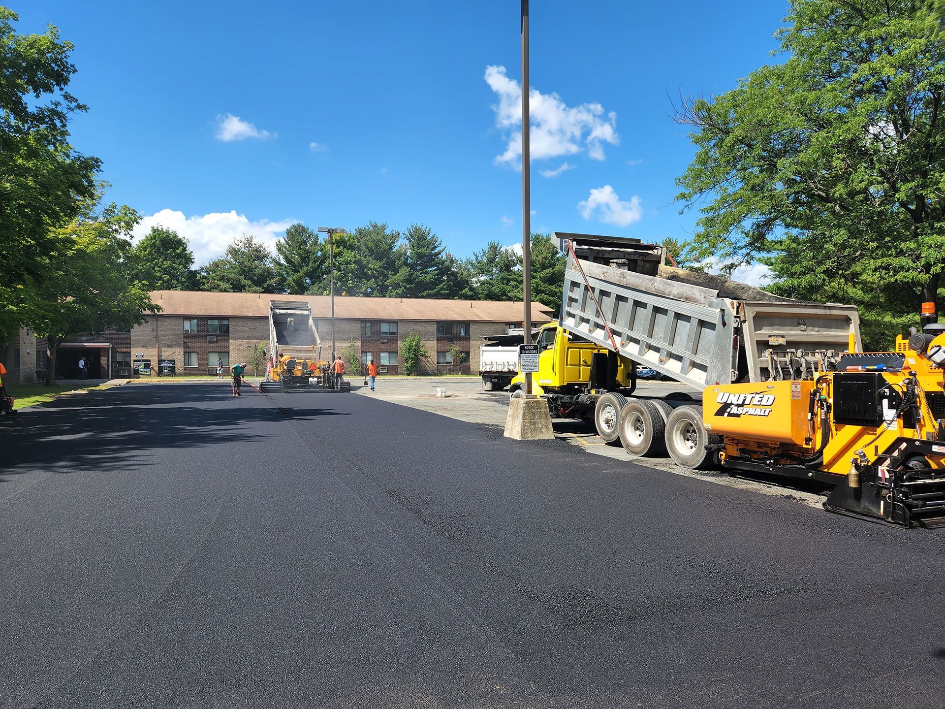 a dump truck is being loaded with asphalt in a parking lot