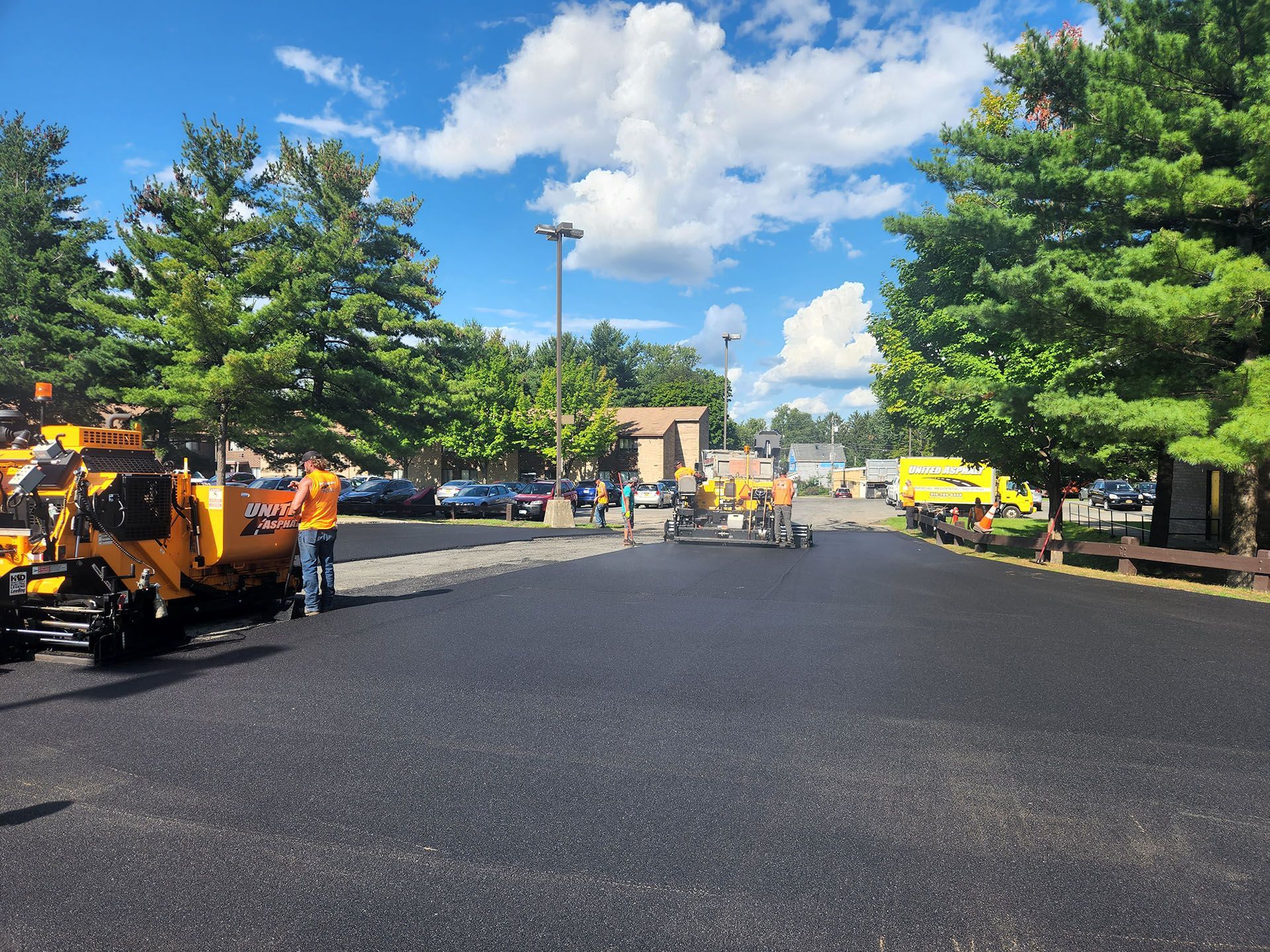 a road is being paved in a parking lot on a sunny day