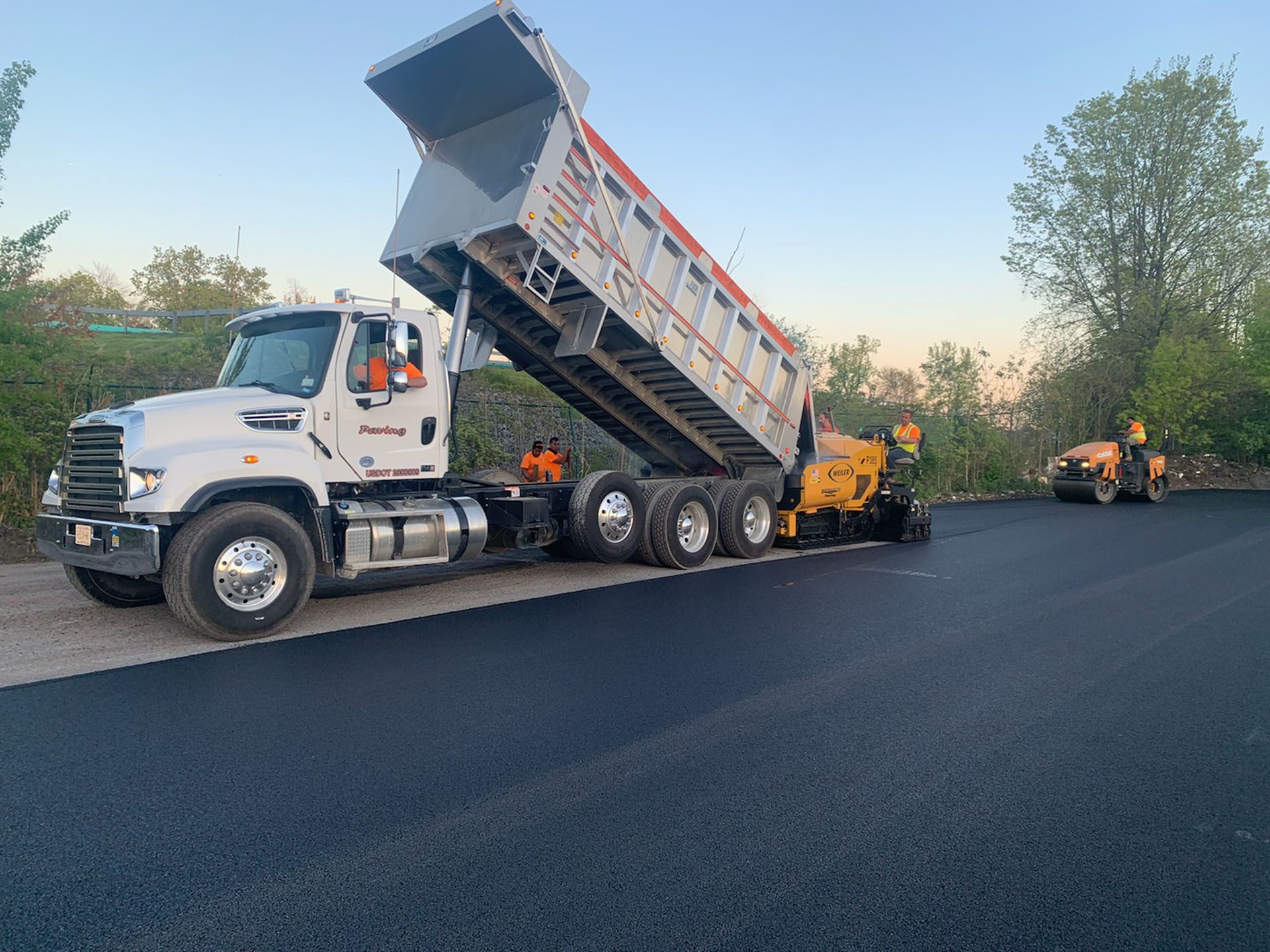a dump truck is being loaded with asphalt on a road .