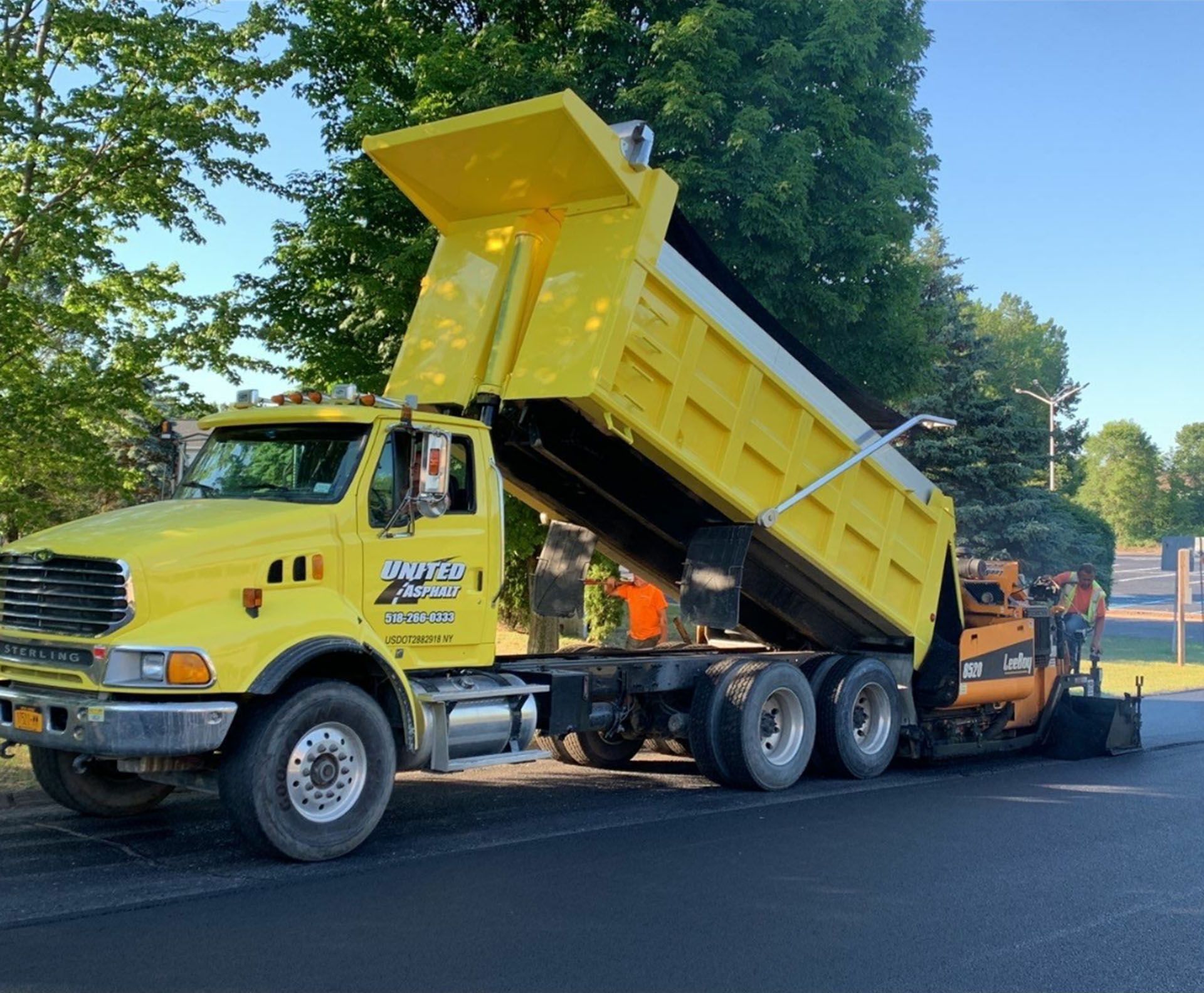 road paving project in progress with yellow dump truck