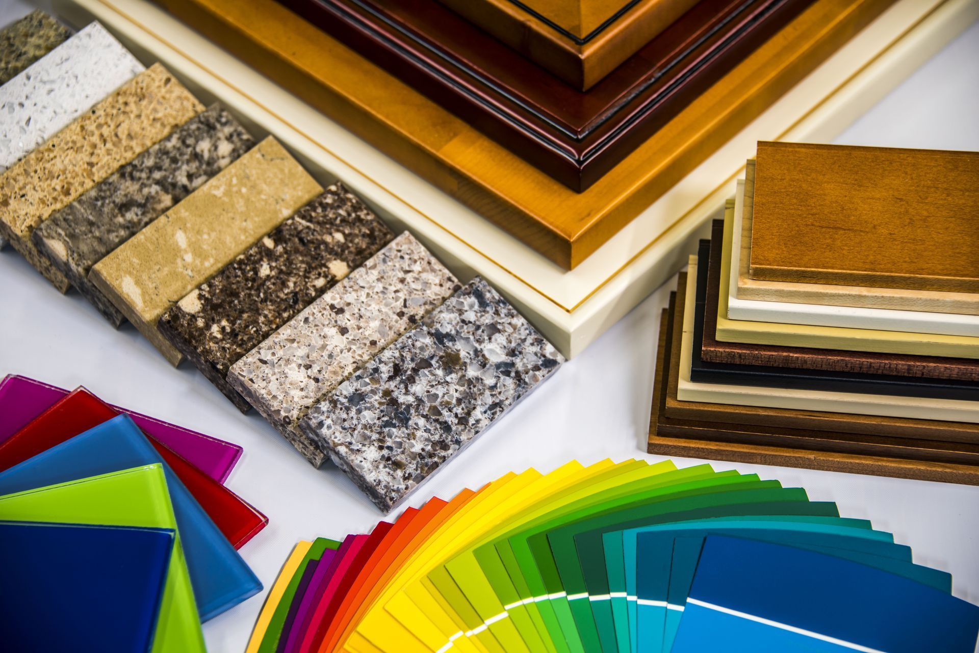 Assorted countertop and flooring samples with colorful swatches fanned out on a white surface