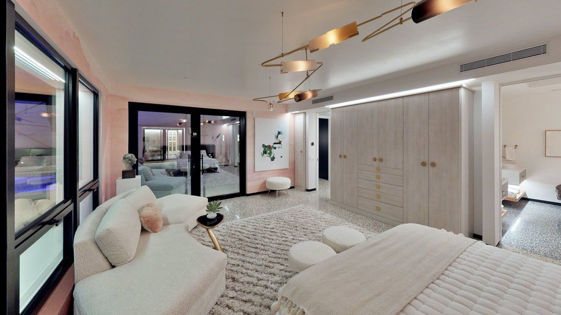 Bright modern bedroom with a bed, sofa, wardrobe, and large windows opening to a city view