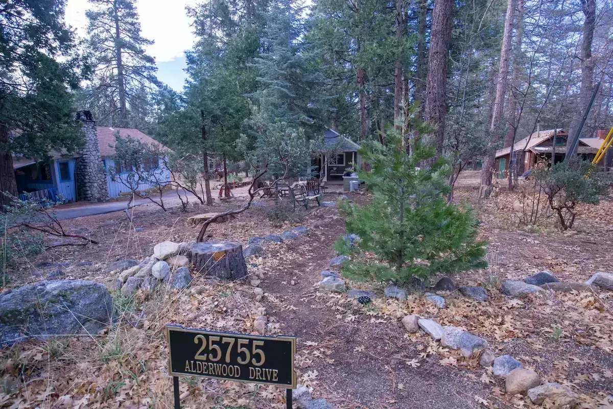 Wooded campsite with cabins, rocks, and a small sign in the foreground