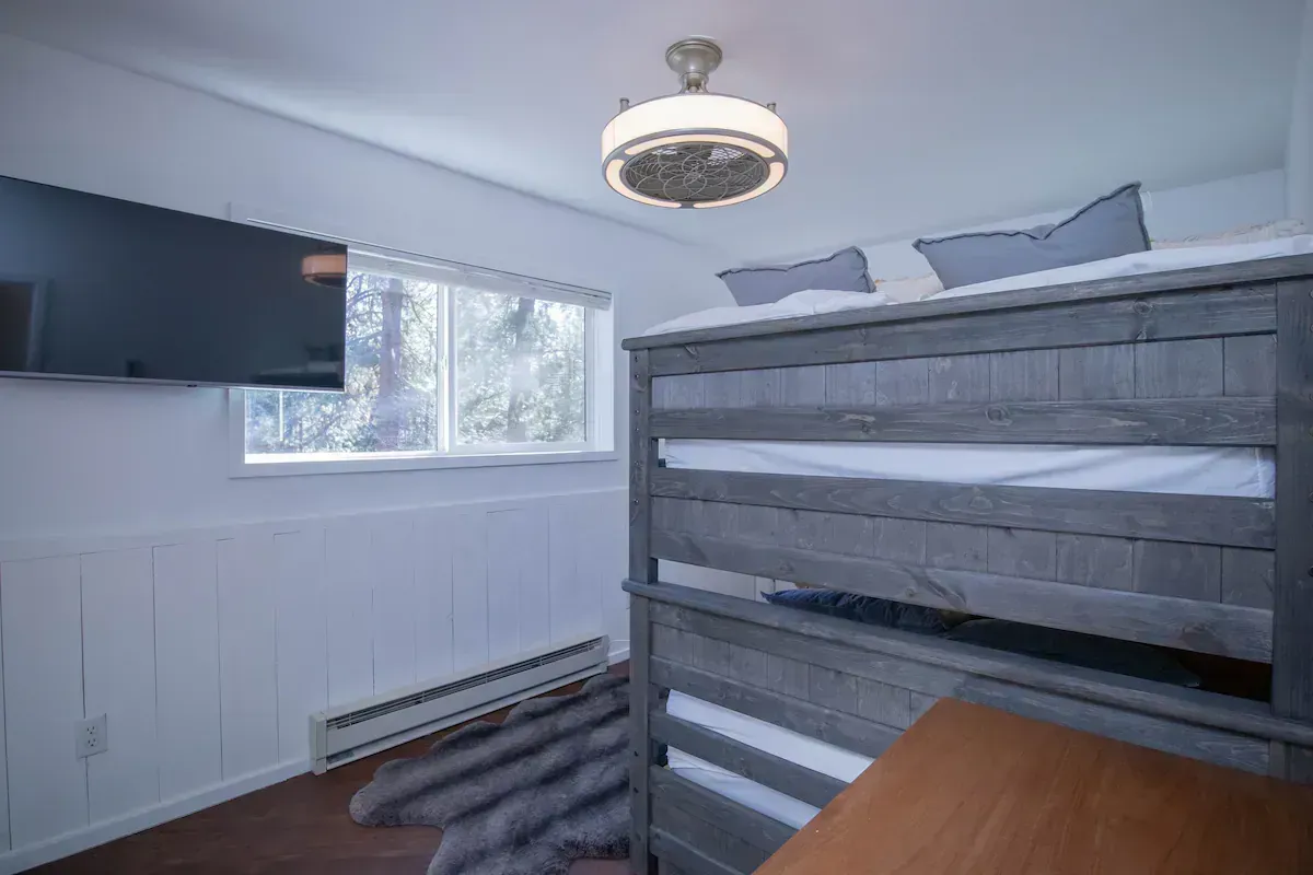 Small bedroom with a bunk bed, window, wall-mounted TV, and gray walls.