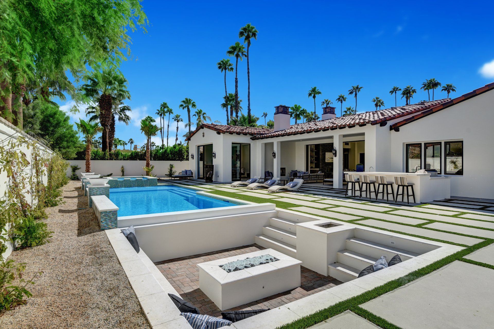 Modern patio with outdoor dining table, desert plants, and warm walkway lights at dusk