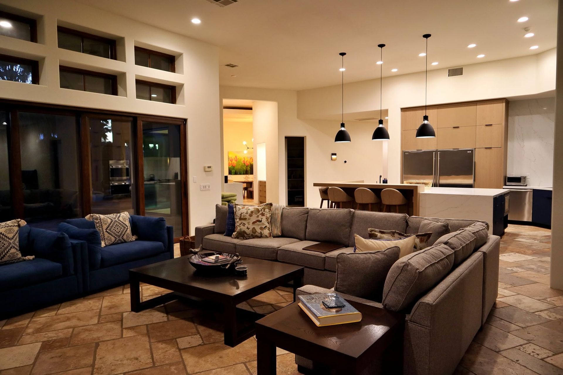 Modern living room with gray sectional, blue chair, coffee table, and open kitchen in the background