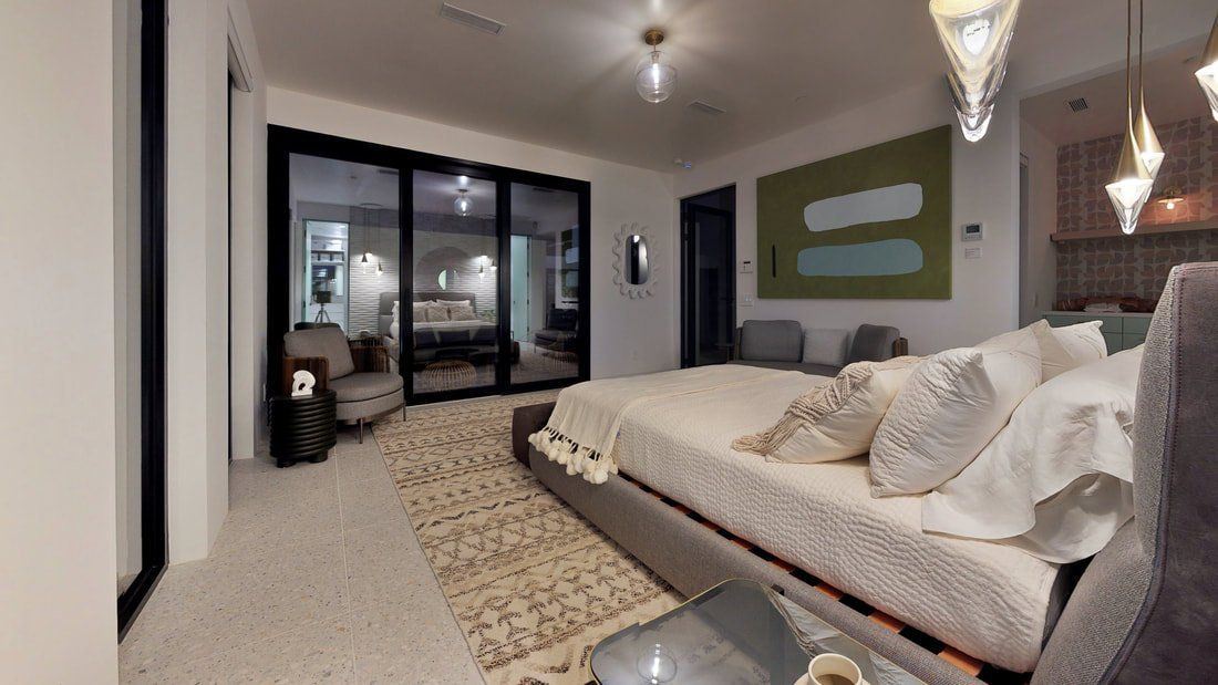 Modern bedroom with a large bed, glass closet doors, pendant lights, and a neutral rug