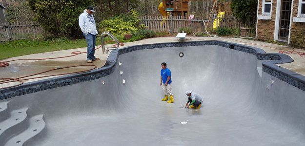 Men in an empty pool, doing repairs or cleaning.
