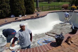 Pool being resurfaced by three workers; white paint covers the interior.