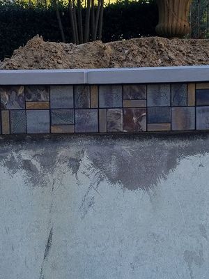 Close-up view of a pool with multi-colored tile border and concrete coping.