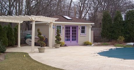 Poolside shed with lavender doors and attached pergola.