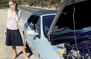 A lady speaking through phone beside the broken car