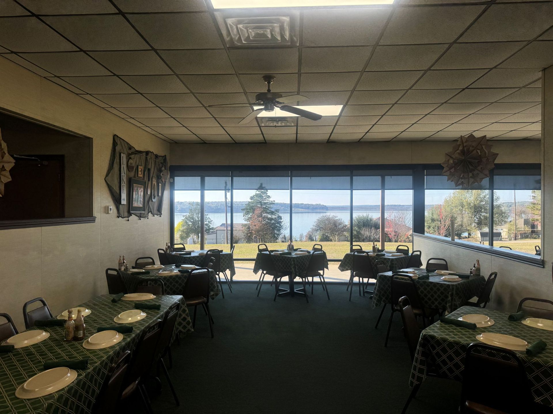 Restaurant dining room with tables set, large window with lake view.