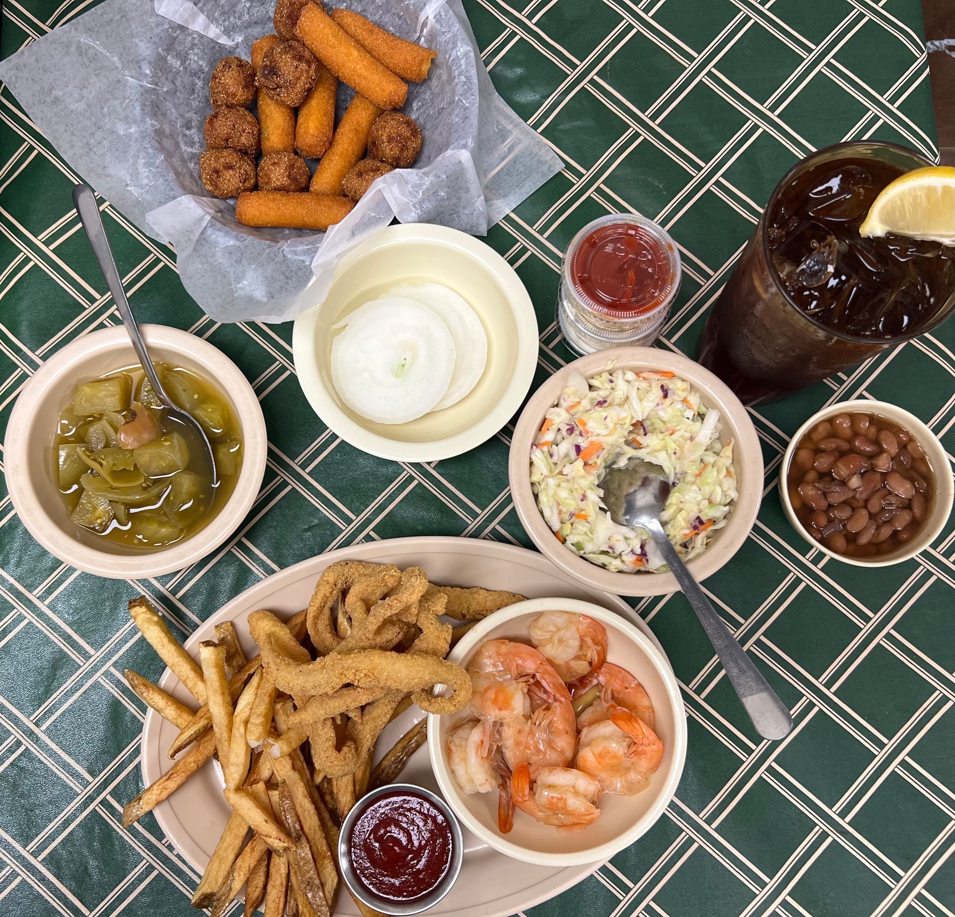 Seafood platter with fries, shrimp, and sides like coleslaw, beans, and onion rings, plus tea.