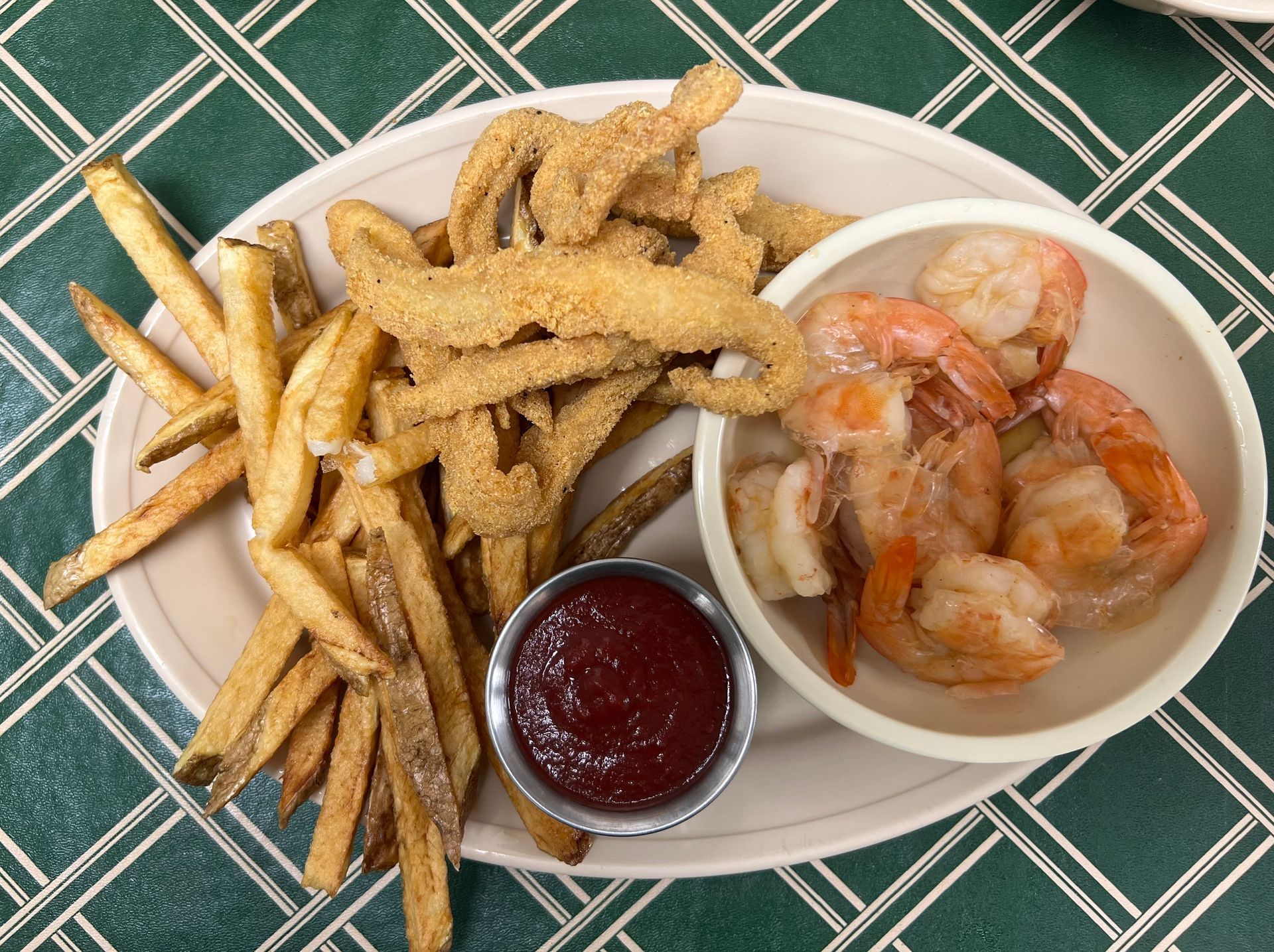 Plate with fried fish, shrimp, fries, and ketchup.