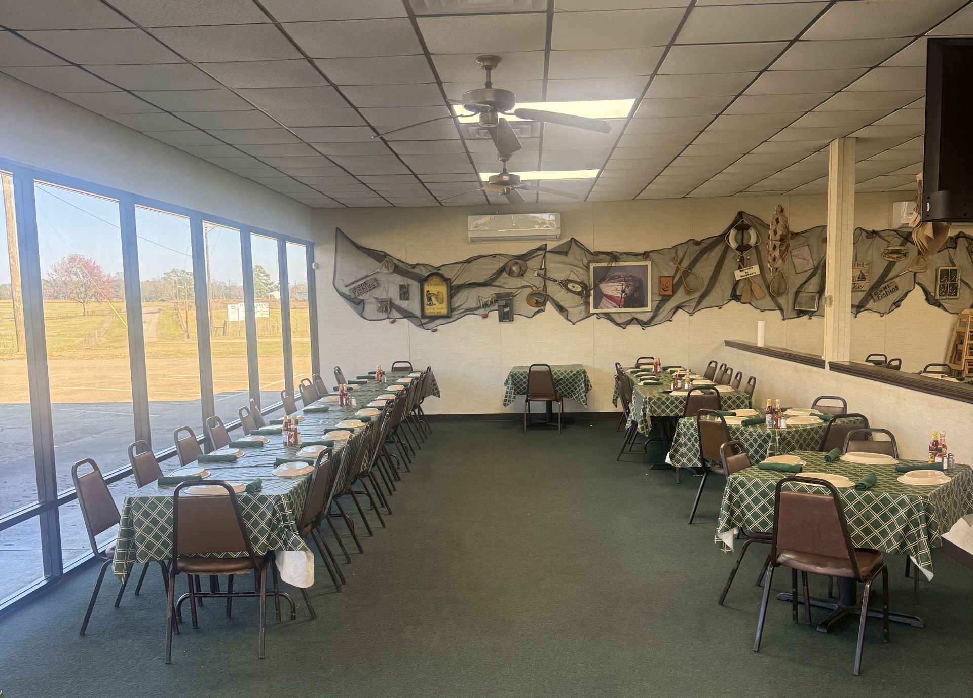 Restaurant interior with tables set for dining, green tablecloths, and a mural on the wall.