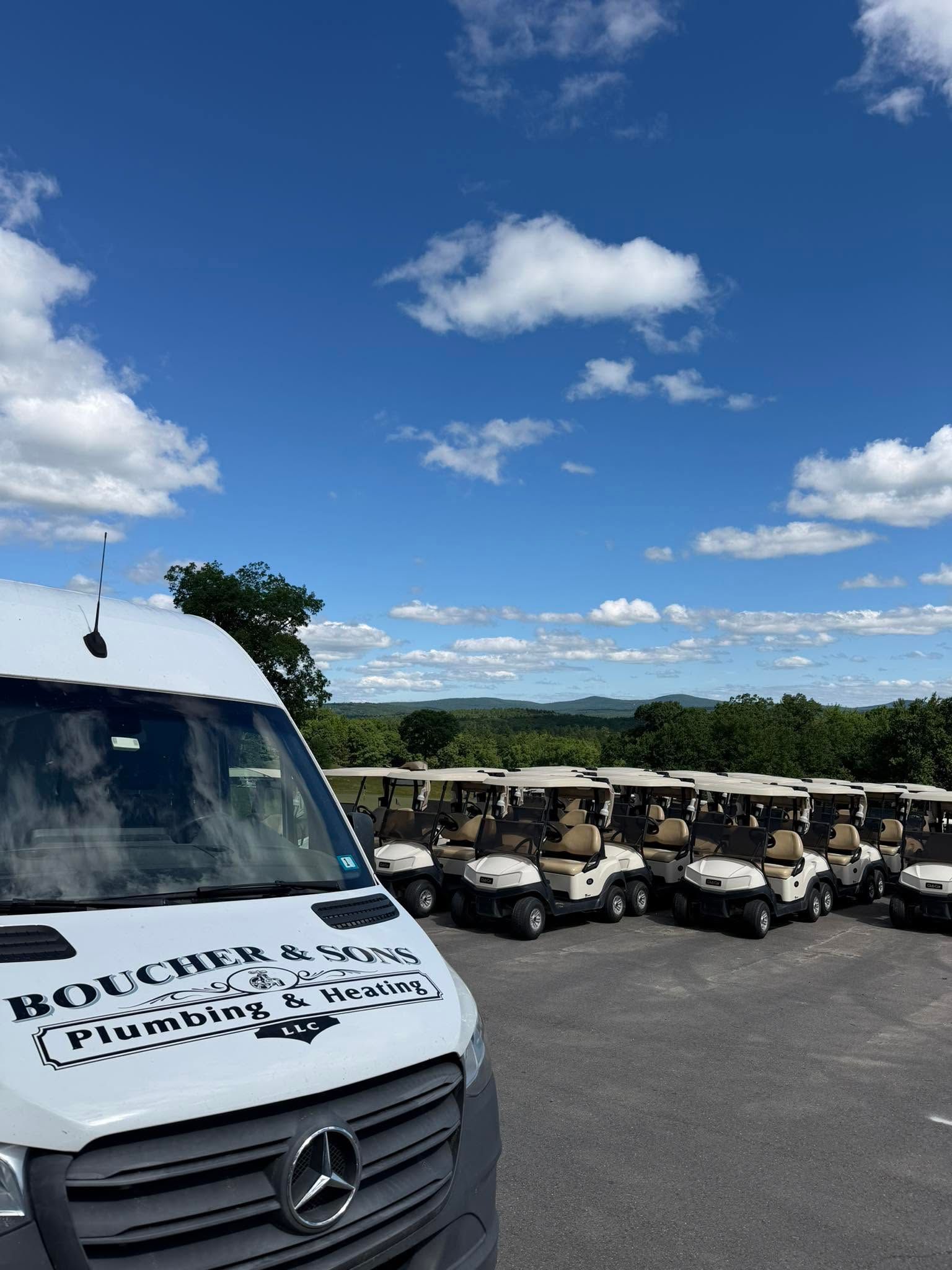 White Mercedes van beside rows of golf carts under a bright blue sky.