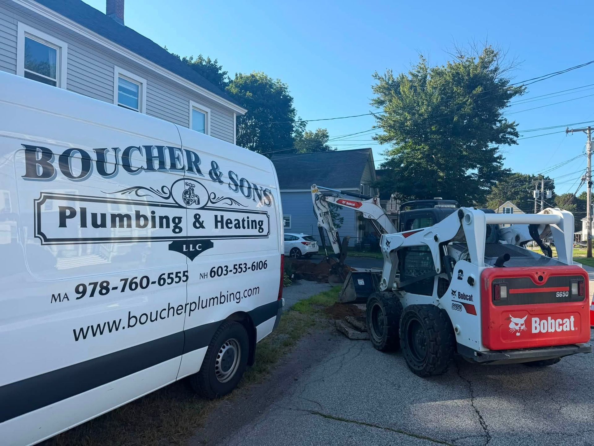 Boucher & Sons Plumbing van beside a Bobcat loader at a suburban work site