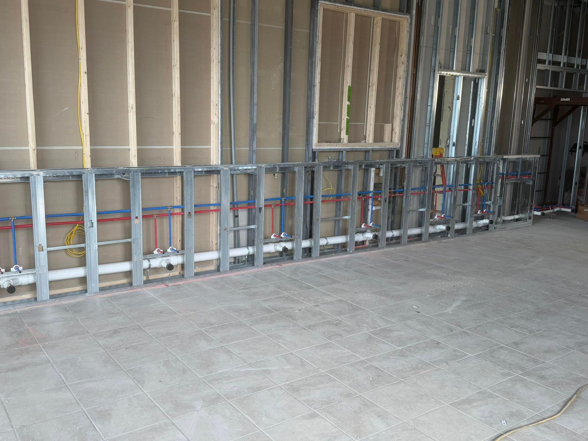 Construction site interior with metal framing along unfinished walls and a concrete floor