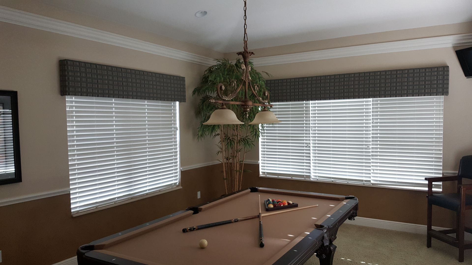 Pool table in a room with blinds, fabric valances, and an indoor tree.