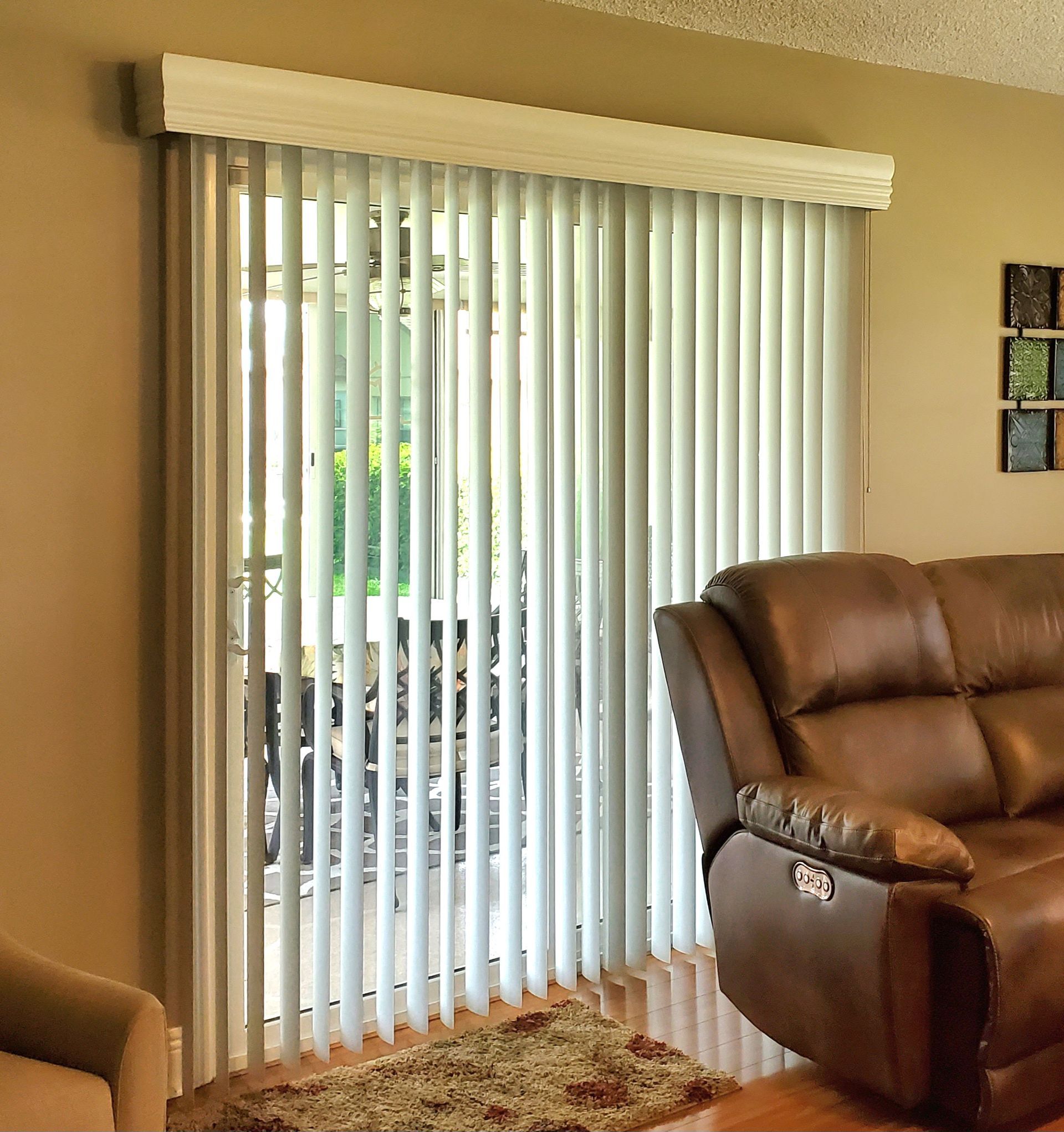 Vertical blinds cover a sliding glass door; a brown recliner sits nearby.