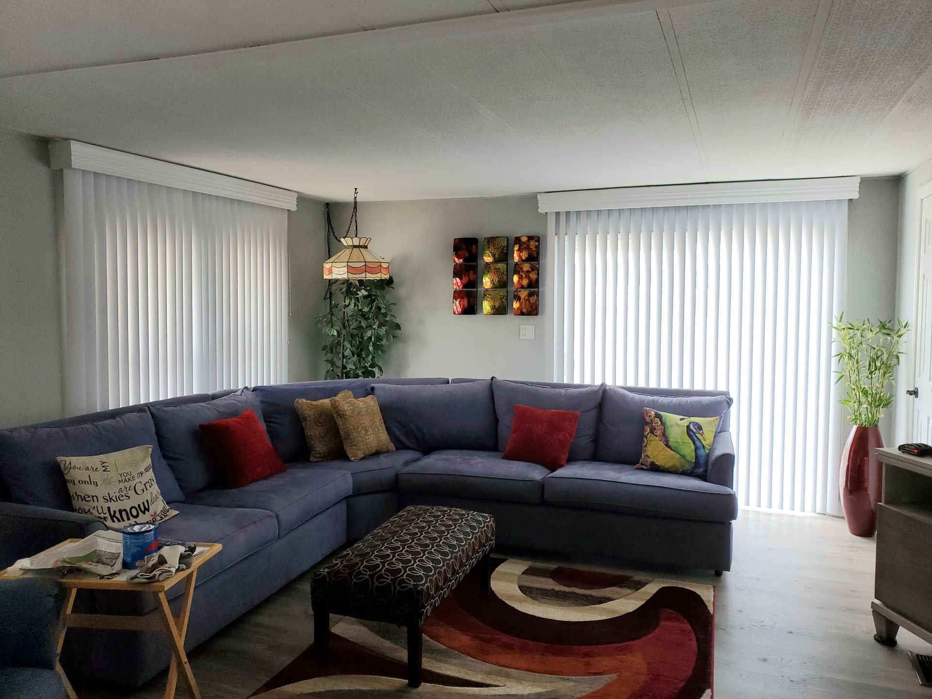 Living room with blue sectional sofa, patterned rug, and white blinds.