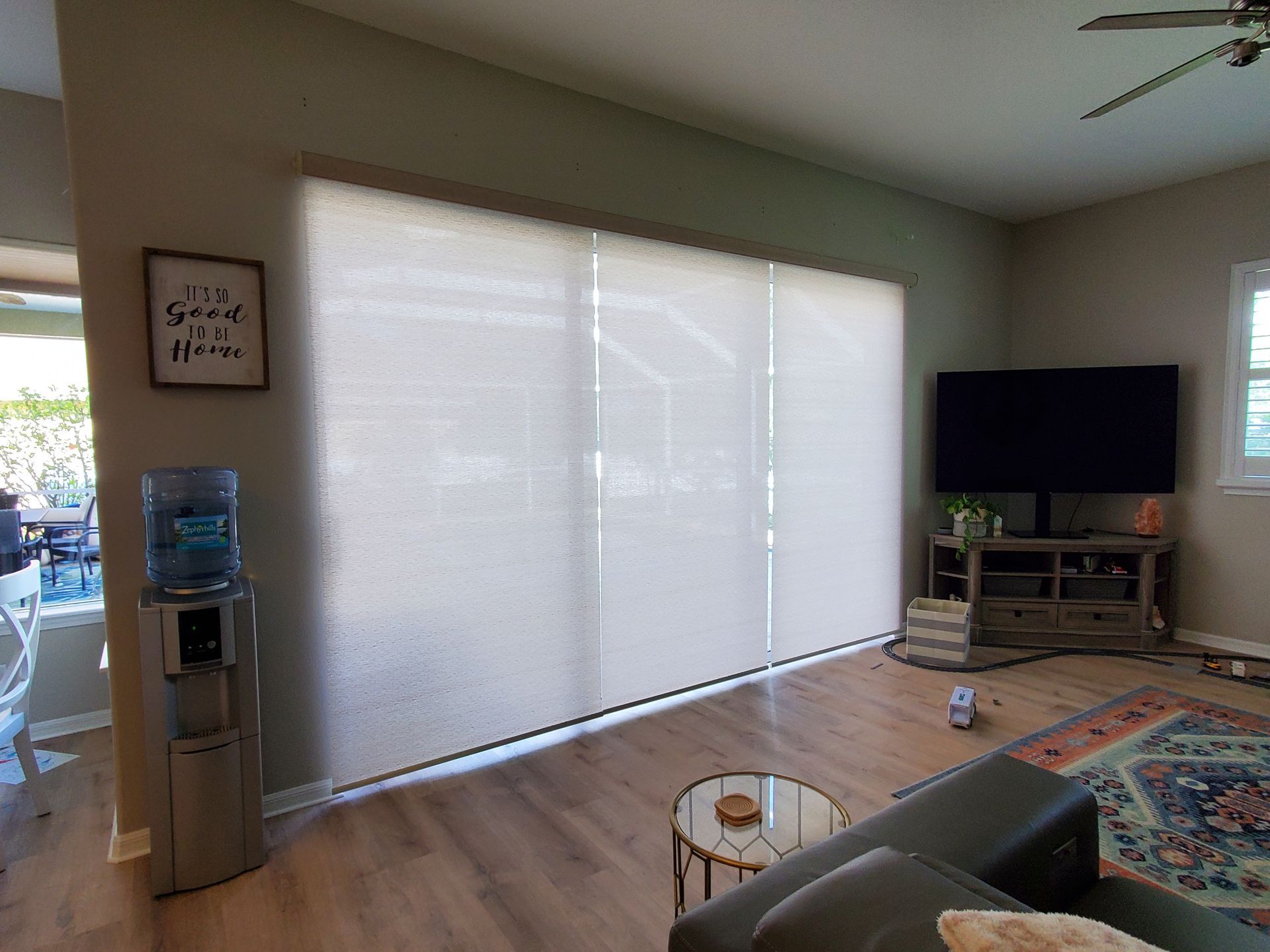 Living room with closed blinds, TV, water cooler, and a small table.