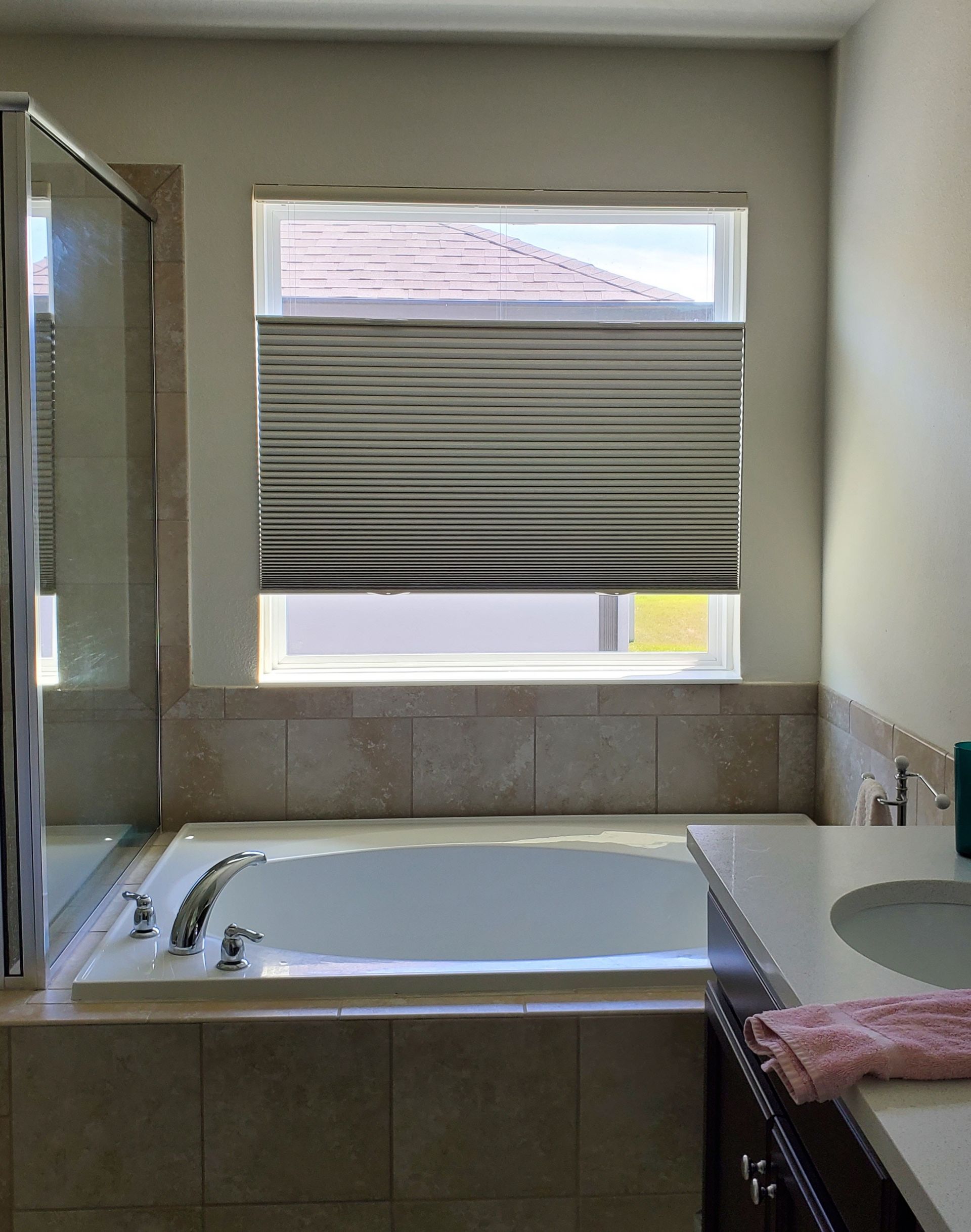 Bathroom with a bathtub beneath a window with striped blinds.
