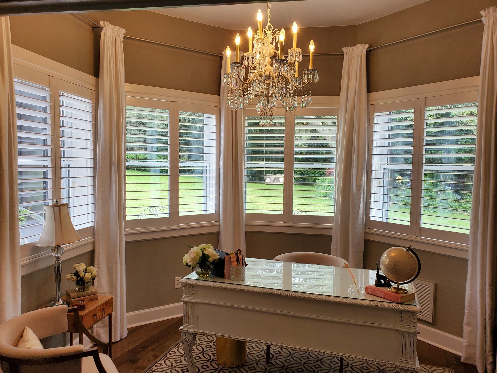 Office space with bay windows, white shutters, and a crystal chandelier.