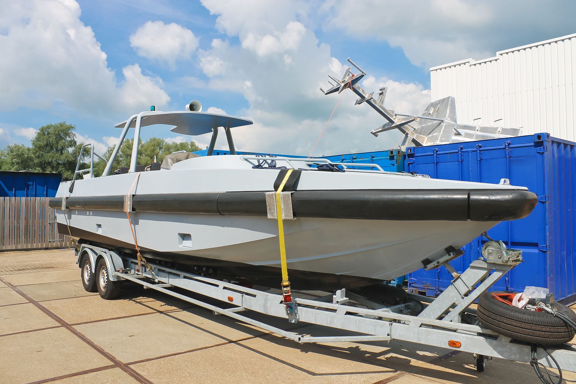 A boat is sitting on a trailer with a blue container in the background