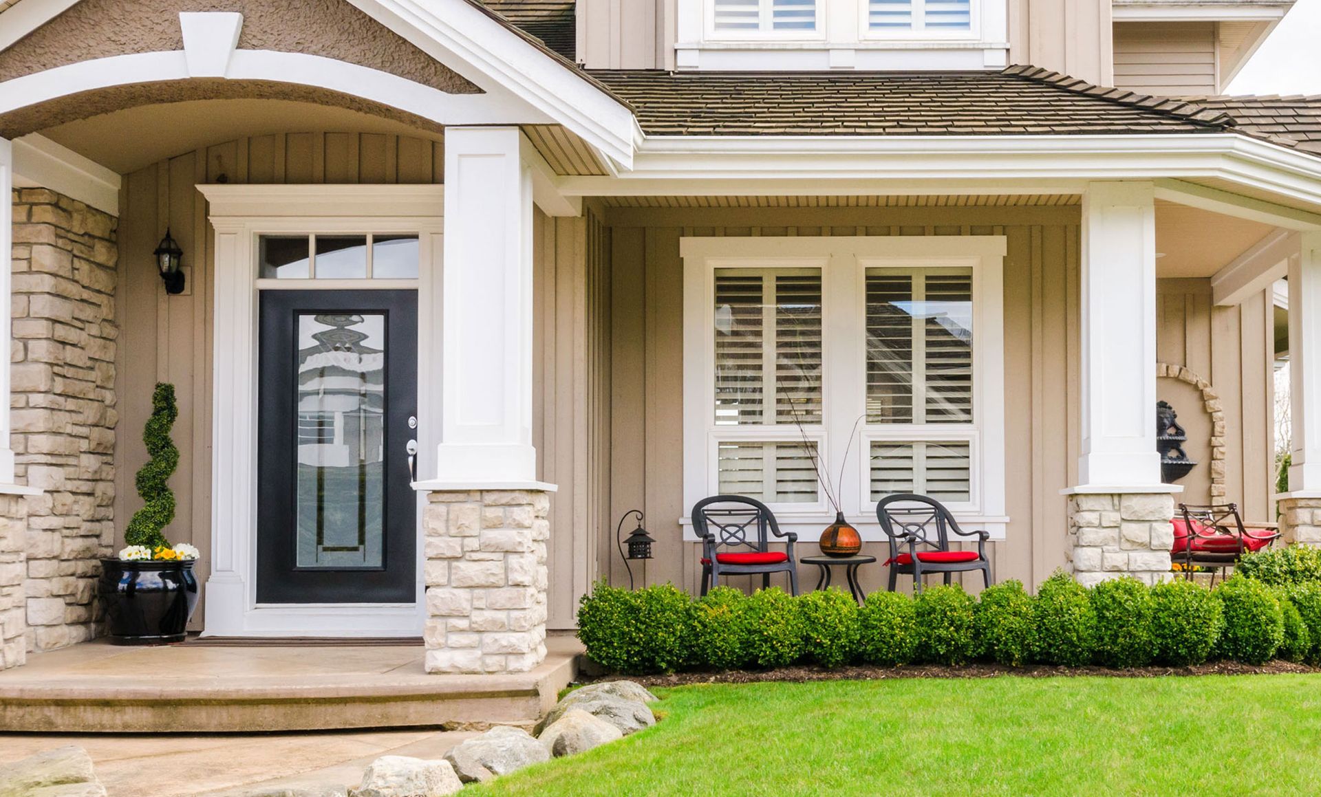 The front of a house with a porch and chairs in front of it