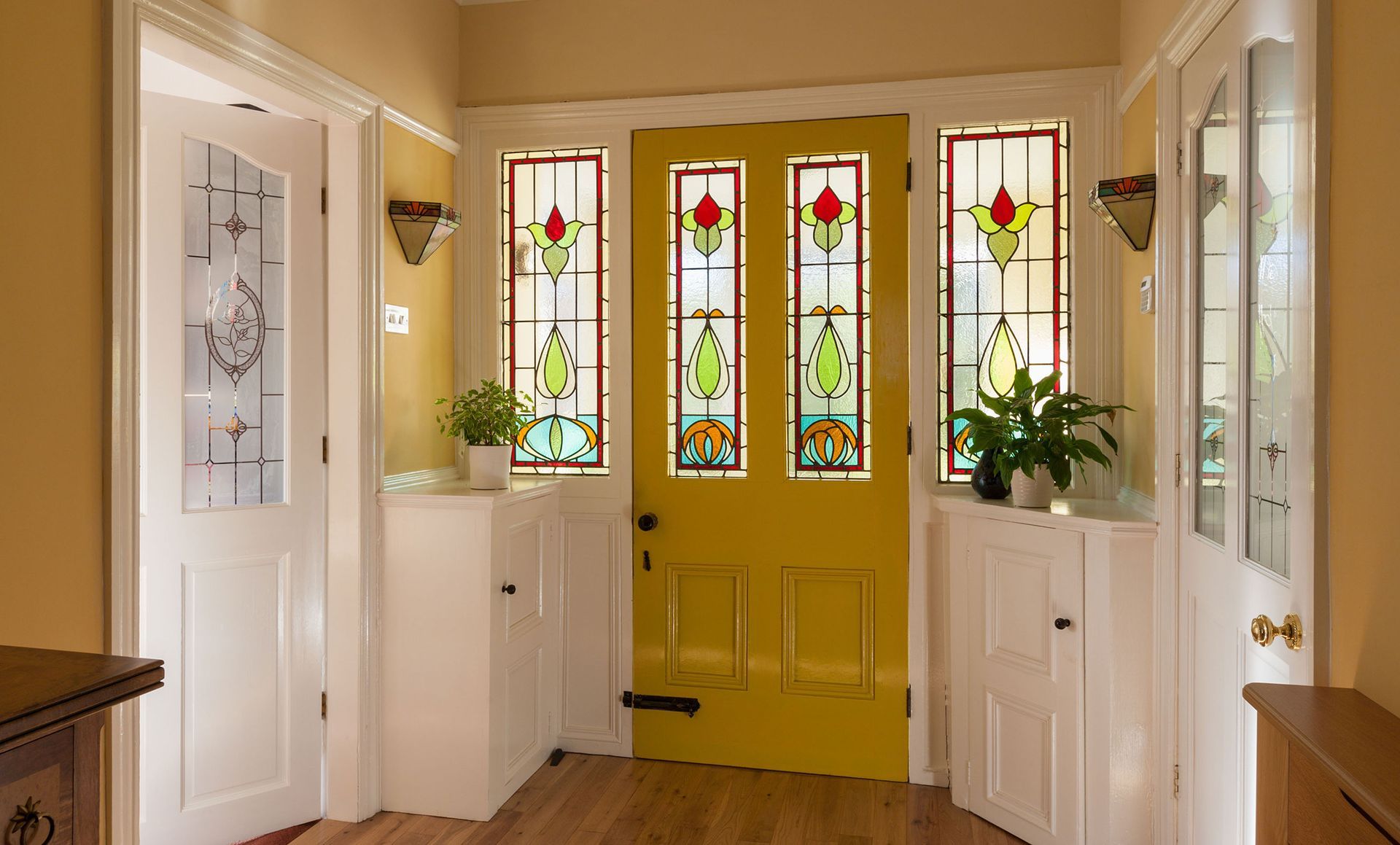 A hallway with a yellow door and stained glass windows