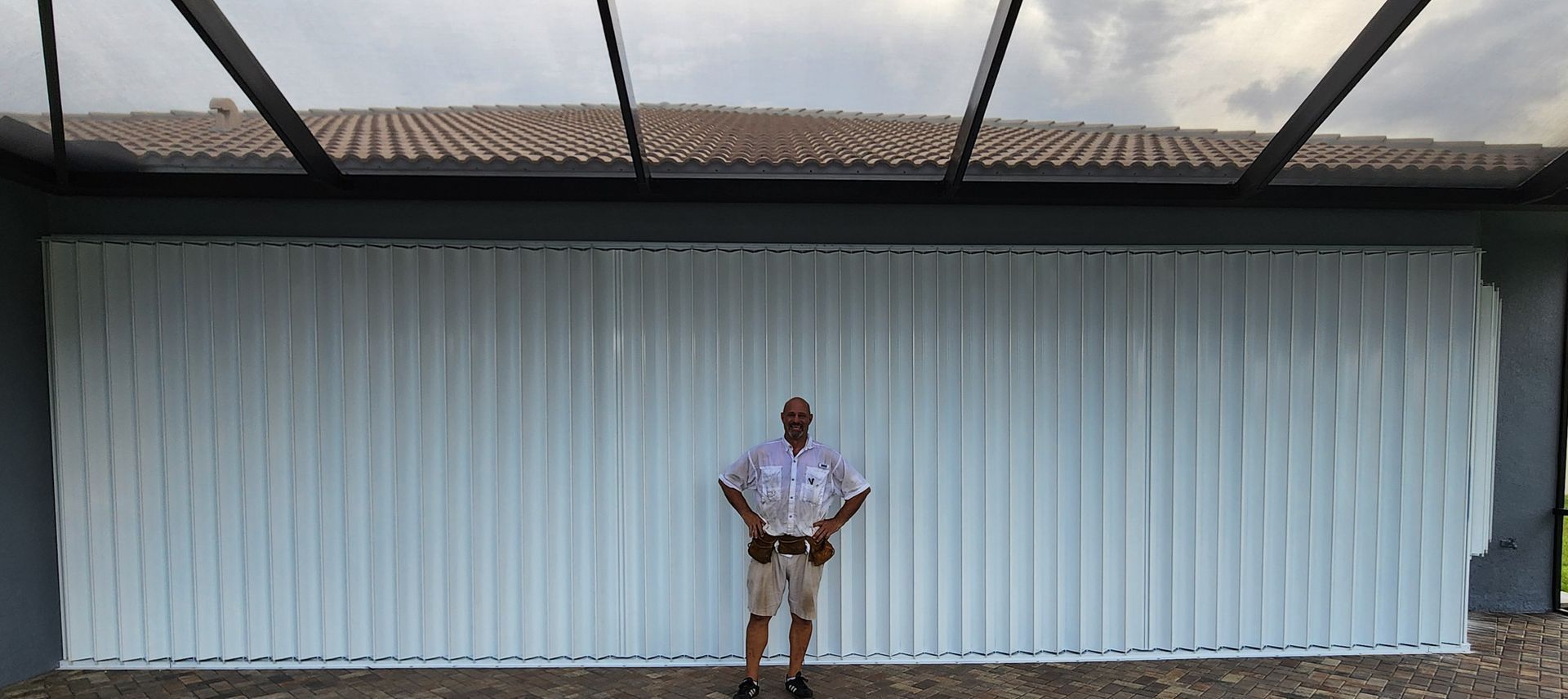 A man is standing in front of a large white garage door