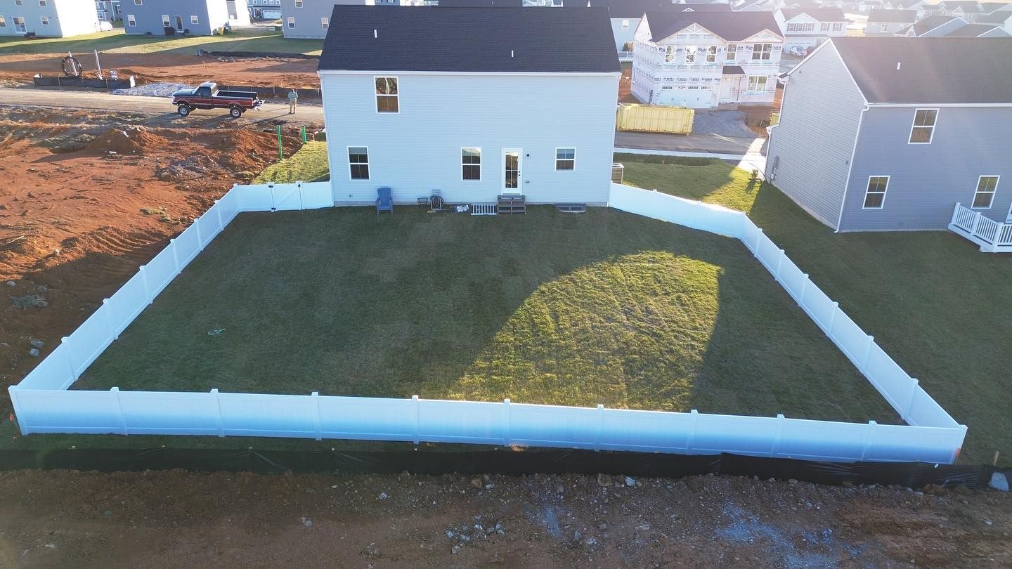 an aerial view of a house with a white fence around it