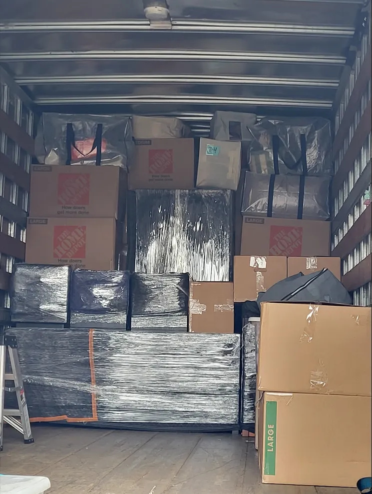 Truck cargo area loaded with stacked boxes and shrink-wrapped pallets of goods