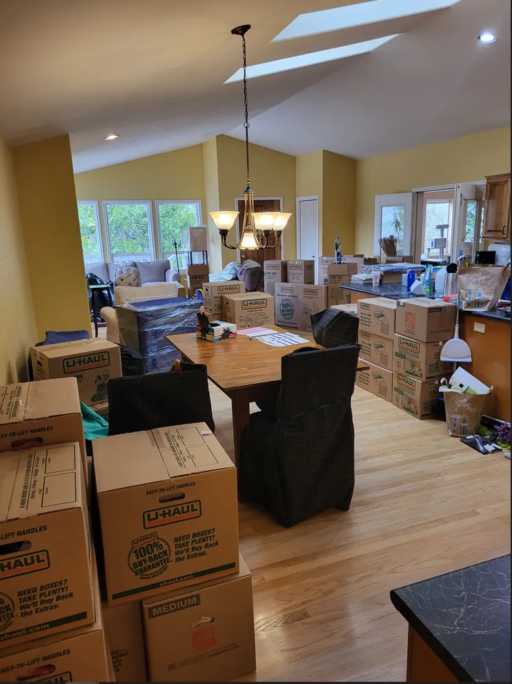 Packed dining room with moving boxes and furniture during a home move