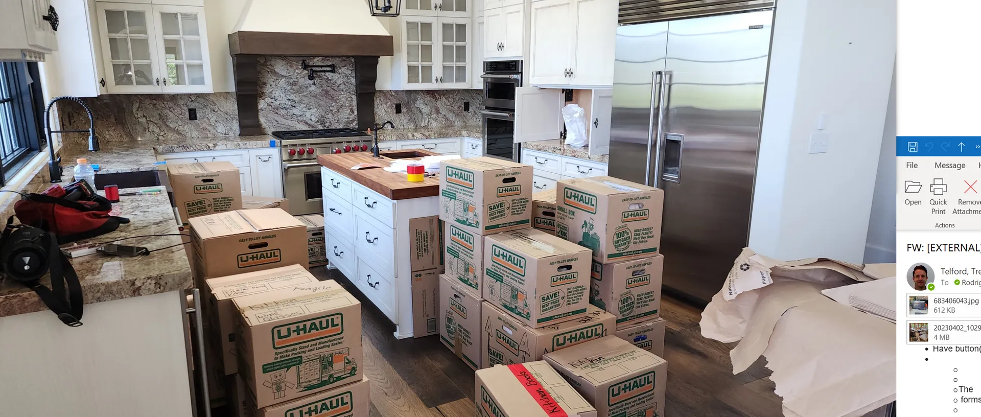 Kitchen cluttered with many cardboard boxes, a white stove, and packed items on counters and floor