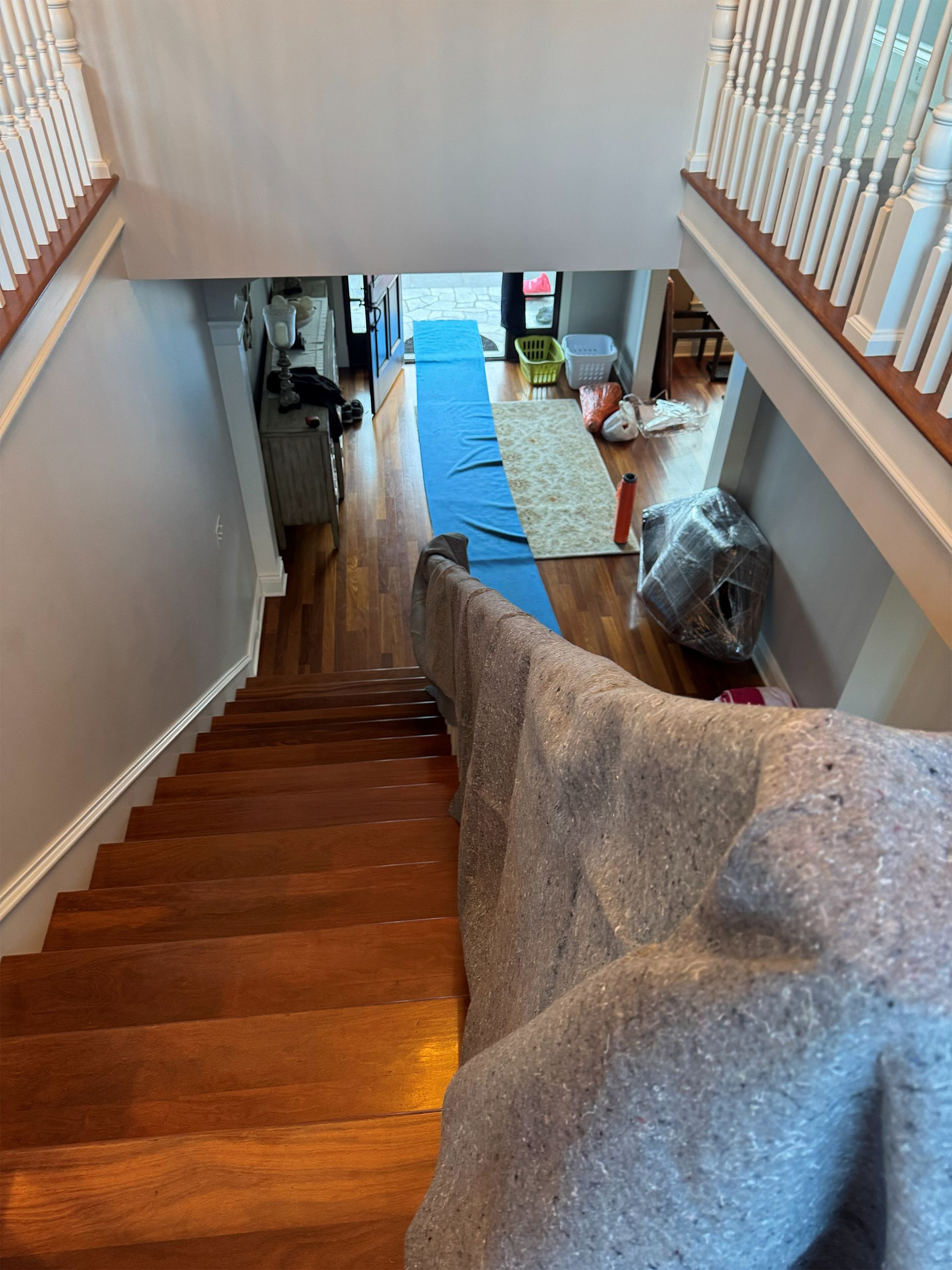 Staircase overlooking a hallway with blue runner, wood steps, and a chair covered in gray fabric