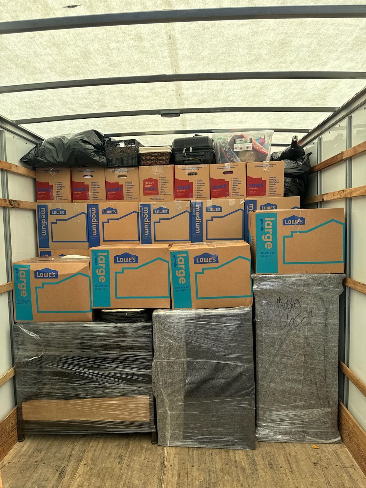 Packed moving truck with stacked cardboard boxes and wrapped items inside.